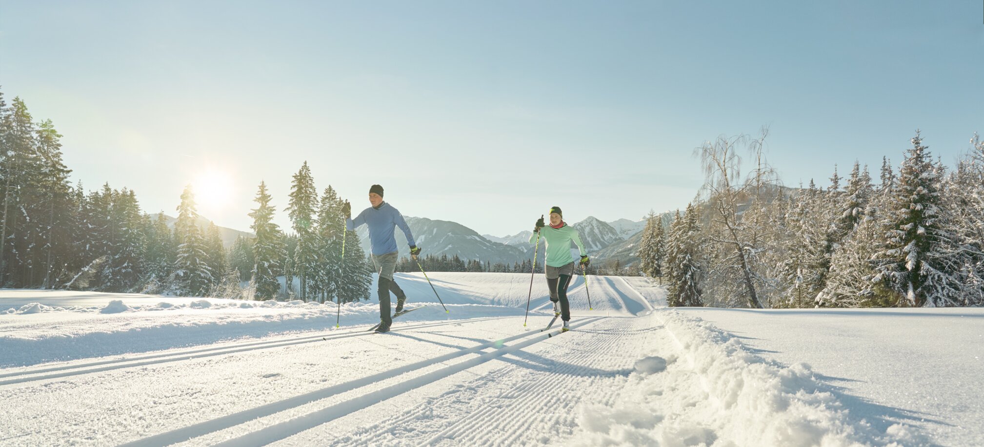Two cross-country skiers running on a sunlit trail | © Peter Burgstaller